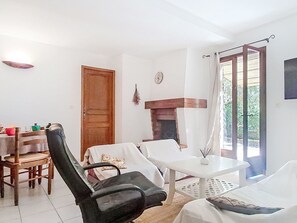 Une pièce comprenant une table à manger, des chaises, un canapé, une cheminée et une fenêtre avec des rideaux.