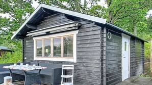 Eine Holzhütte mit einer Terrasse, einem Tisch und Stühlen sowie einem Fenster.