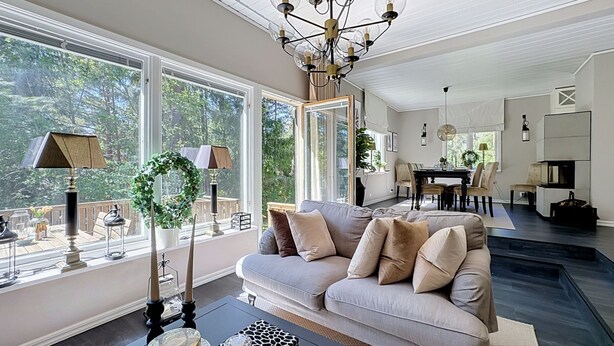 A spacious living room with a large sofa, a chandelier, and a dining area with a table and chairs. - Skärgårdshem by Interhome (Dalarö)