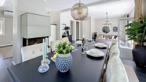A dining area with a black table, white chairs, a large vase, and a chandelier. - Skärgårdshem by Interhome (Dalarö)