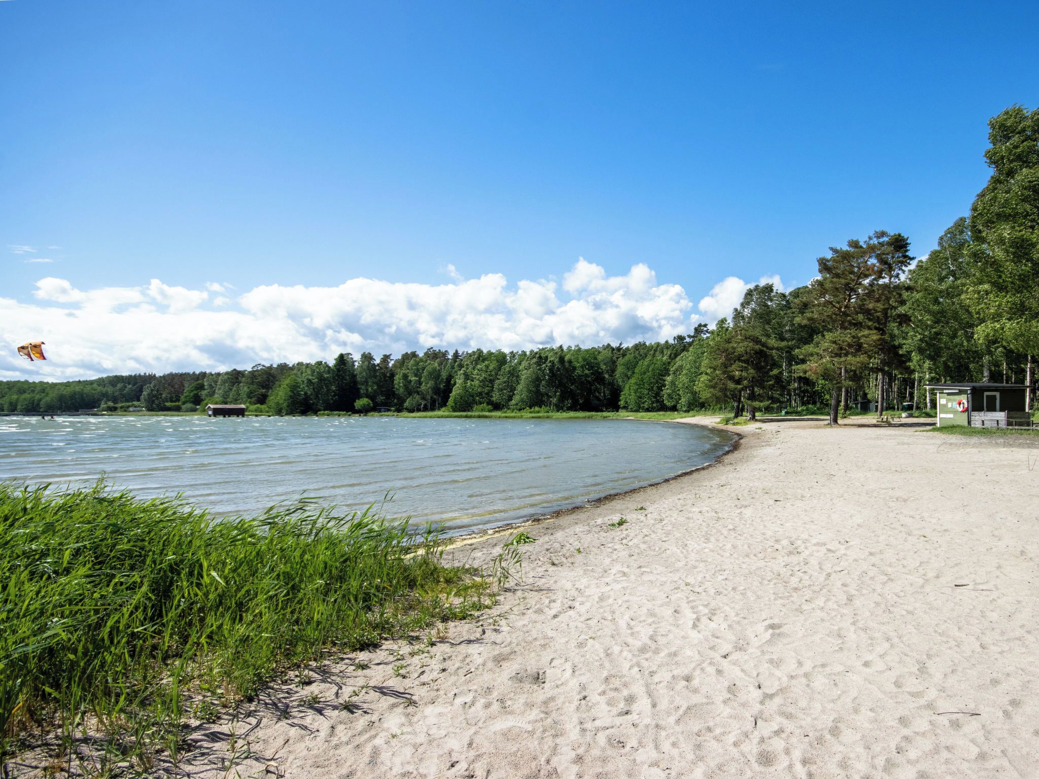 A beach with a sandy shore, a small shelter, and a forested area in the background. - Skärgårdshem by Interhome (Dalarö)