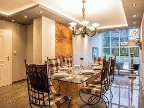 A dining room with a glass table, plaid chairs, and a chandelier. - Villa 10 by Interhome (Ötz)