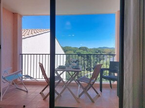 A balcony with a table, chairs, and a view of a green landscape. - Le Luberon by Interhome (Six Fours La Coudoulière)