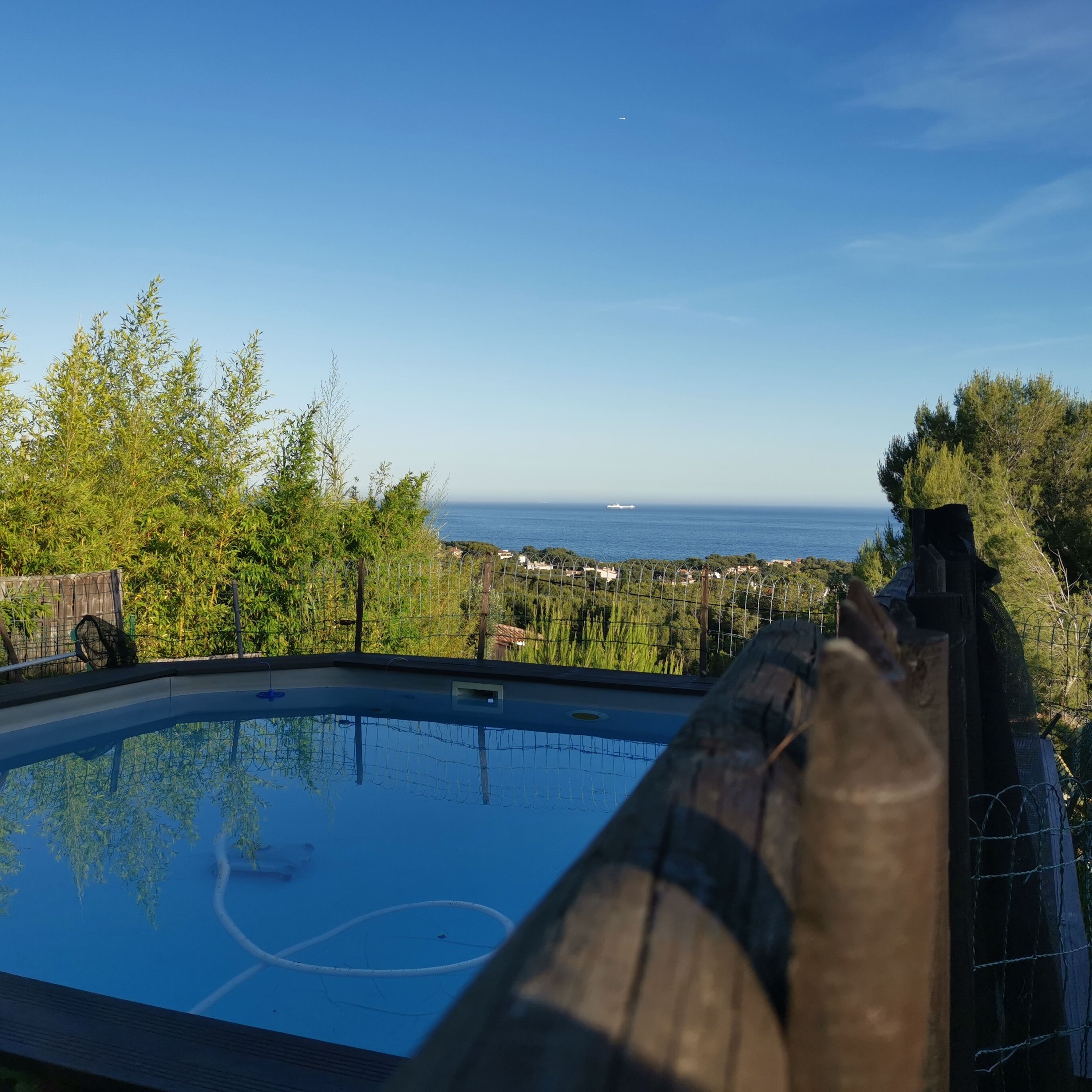 A swimming pool with a view of the sea and distant buildings.