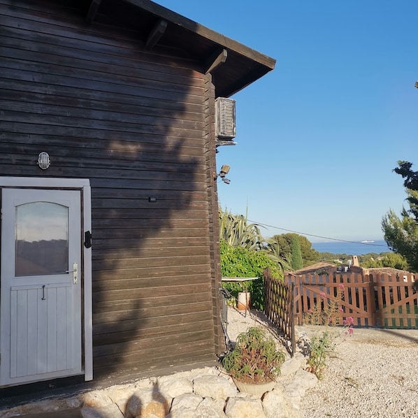 Un edificio de madera con puerta blanca, una cámara de seguridad y vista al mar.