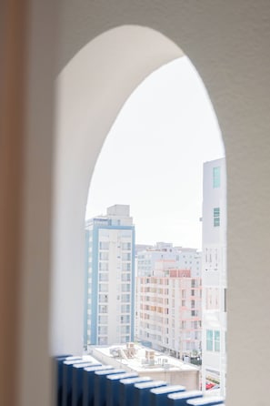 A view through an arched window of a cityscape with multiple buildings. - Da Vinci Suites (San Juan)