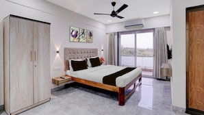 A modern bedroom with a large bed, a wardrobe, a ceiling fan, and a large window with curtains. - Palette Virar Mumbai (Vasai)