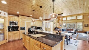 A spacious kitchen with wooden cabinets, a large island, and pendant lighting. - Gold Rush Lodge, 6BR Hot Tub, GameRoom, Sleeps 16+ (Big Bear Lake)