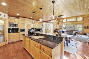 Una cocina amplia con armarios de madera, una isla grande e iluminación colgante.