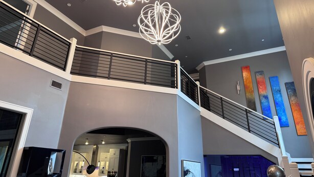 Ein mehrgeschossiges Interieur mit einer Treppe, modernen Leuchten und abstrakter Wandgestaltung.