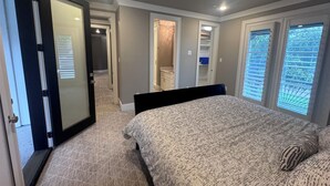 Ein Schlafzimmer mit Bett, Deckenventilator, begehbarem Kleiderschrank und einer Tür zu einem anderen Raum.
