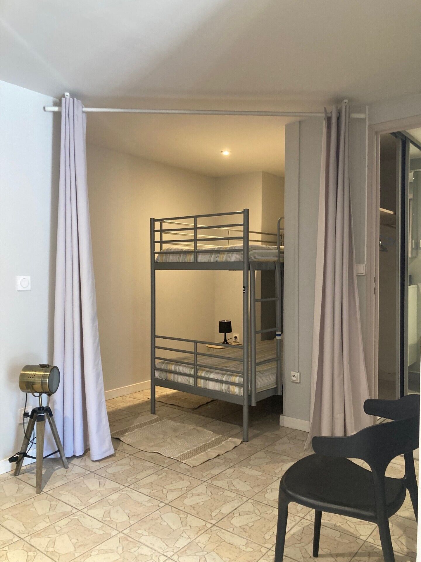 A bunk bed room with a tripod and a chair.