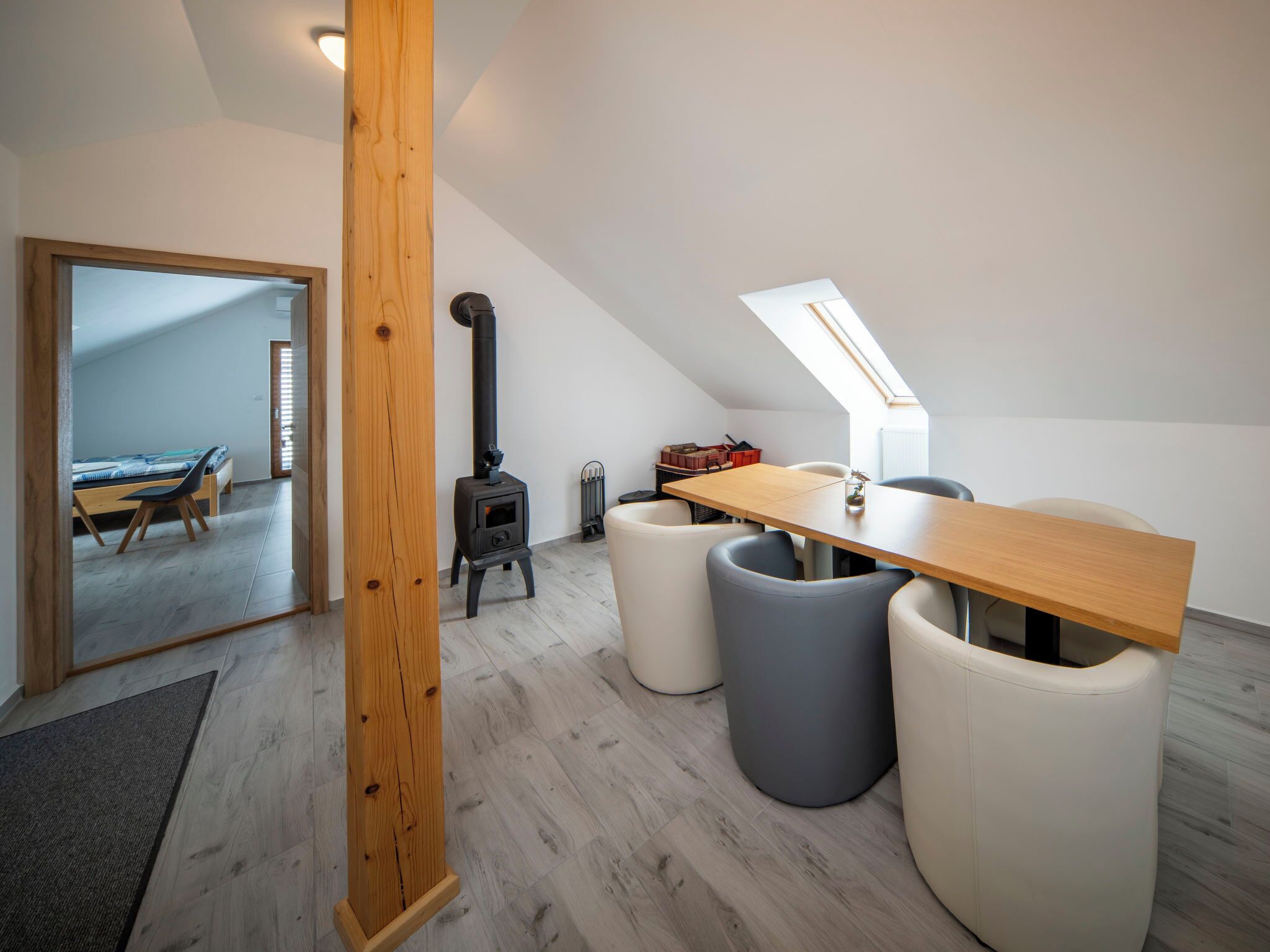 Une chambre de style loft moderne, avec un plafond en pente, une table en bois et un poêle à bois encastré.