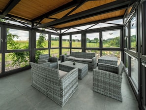 A sunroom with large windows, wicker furniture, and a wooden ceiling. - V Šachu by Interhome (Dačice)