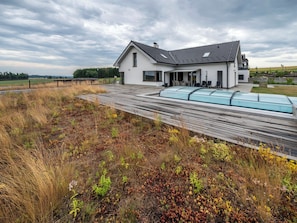 A modern house with a sloped roof, a covered patio, and a garden area with a wooden deck.