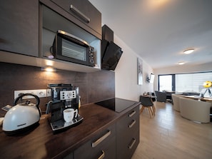 A modern kitchen with a built-in microwave, coffee machine, kettle, and a small dining area with a table and chairs. - V Šachu by Interhome (Dačice)