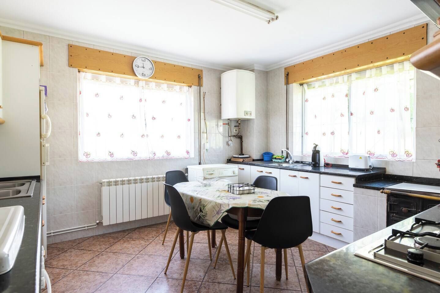 Una cocina compacta con una mesa de comedor, sillas, un reloj y una estufa.
