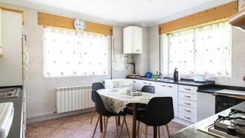 Una cocina compacta con una mesa de comedor, sillas, un reloj y una estufa.