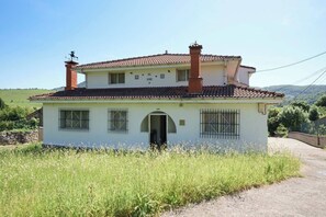 A two-story house with a tiled roof, a chimney, and barred windows.