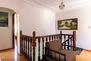 A staircase with wooden balusters leading to a landing where a wicker chair is placed.