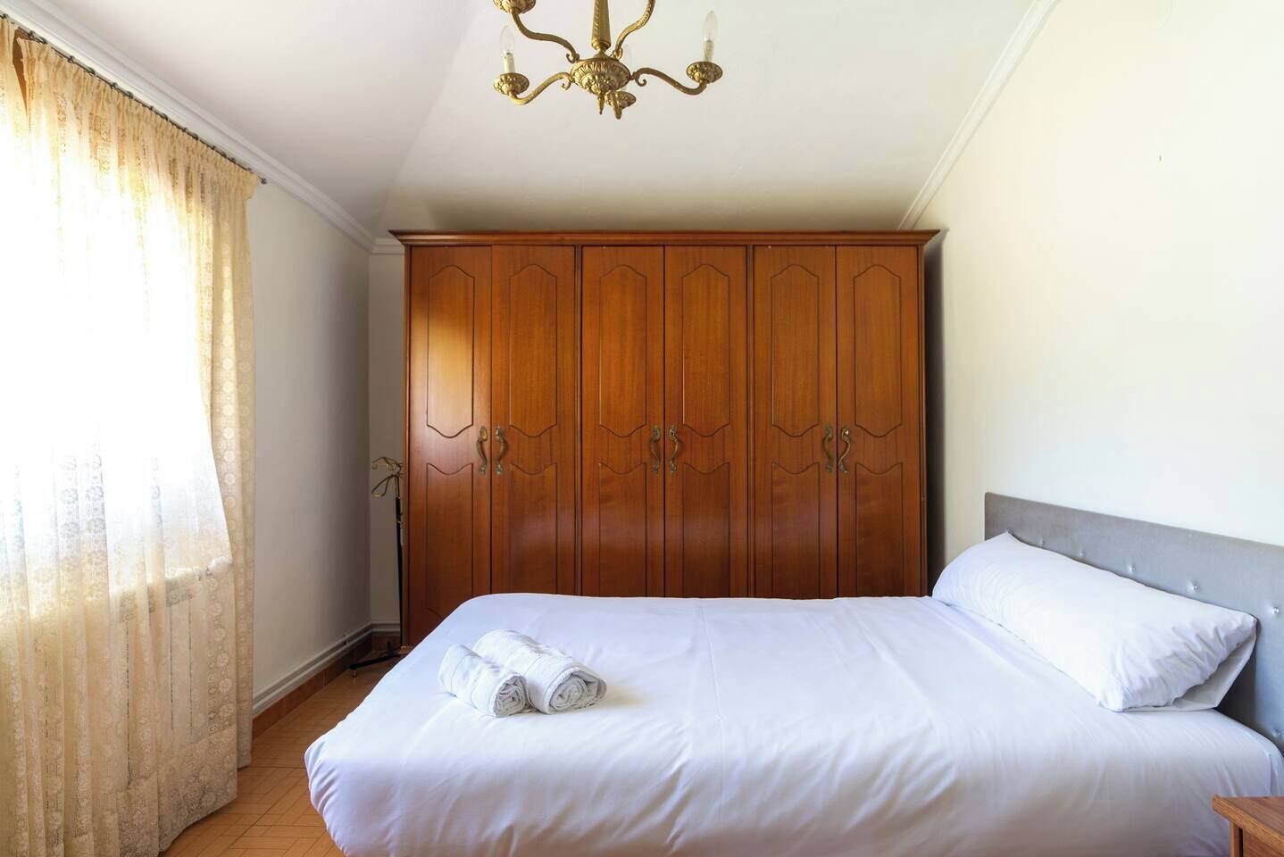 Un dormitorio con una cama, un armario y una araña.