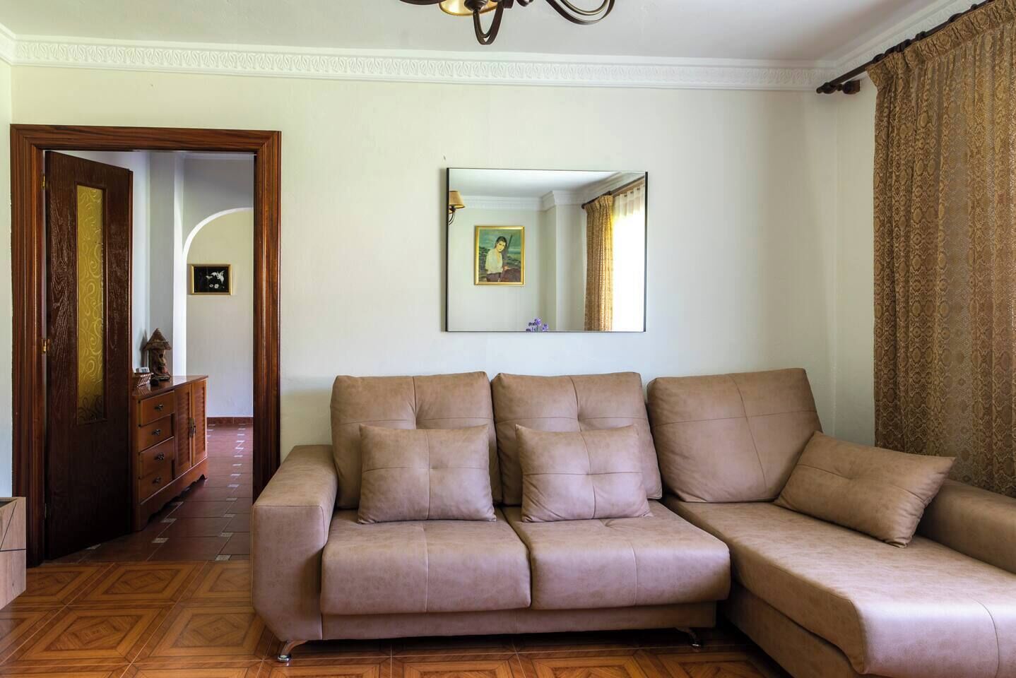 Un salon avec un canapé, un meuble en bois, un miroir et une porte.