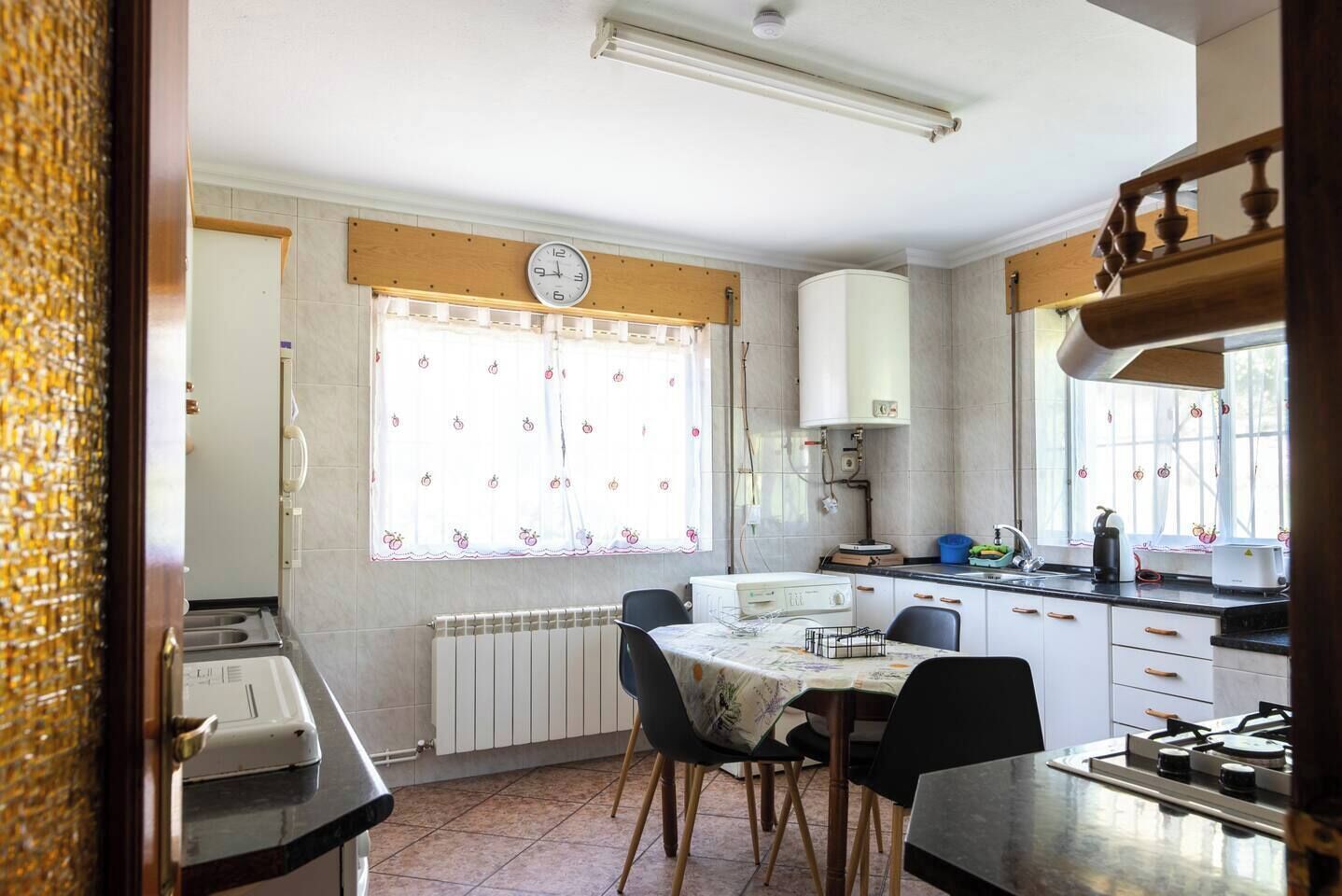 Una cocina compacta con una mesa, sillas, estufa y ventana con cortinas.
