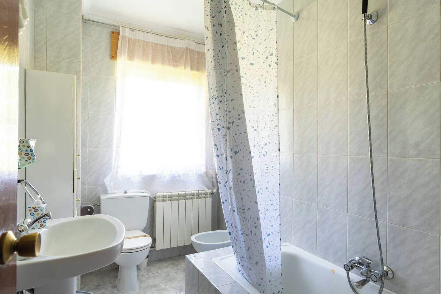 Un baño con inodoro, lavamanos, bañera y ducha.