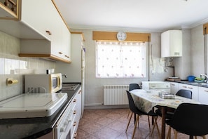 A compact kitchen with a stove, microwave, and a dining table with chairs.