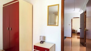 A room with a wardrobe, a bedside table with a lamp, and a mirror on the wall. - Casa Pesquera - by Wehomes (Pesquera)