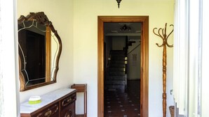 A hallway with a wooden staircase, a coat rack, and a mirror on the wall. - Casa Pesquera - by Wehomes (Pesquera)