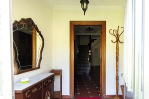 A hallway with a wooden staircase, a coat rack, and a mirror on the wall. - Casa Pesquera - by Wehomes (Pesquera)