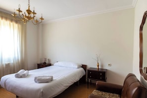 A hotel room with a bed, bedside tables, a lamp, a chair, and a mirror.