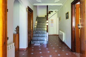 A hallway with a marble staircase, wooden doors, and a tiled floor. - Casa Pesquera - by Wehomes (Pesquera)
