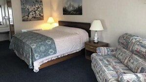 Una habitación de hotel con cama, dos mesitas de noche, un sofá y cuadros en la pared.