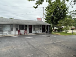 A motel with a single-story structure, a covered porch, and a signboard.