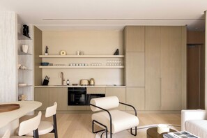 Eine moderne Küche mit eingebauten Geräten, ein Essbereich mit Tisch und Stühlen sowie eine Sitzecke mit einer Couch.