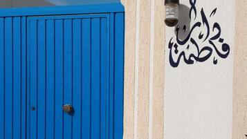 Une porte bleue avec un trou de serrure et un mur orné de calligraphie arabe.