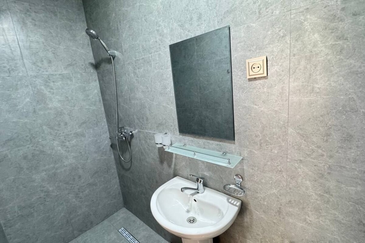 Baño con ducha, lavamanos y espejo.