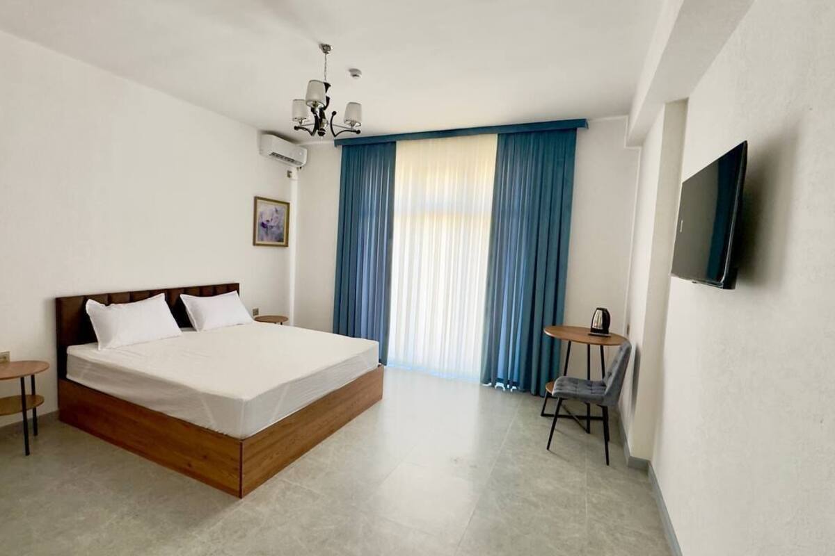 Una habitación de hotel con cama, televisor, una mesita y una silla.