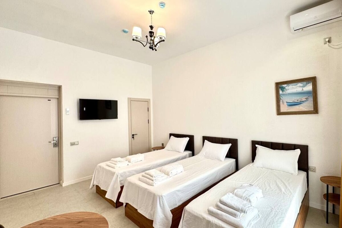 Quarto de hotel com duas camas de solteiro, televisão, ar condicionado e um quadro na parede.