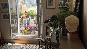 Puerta abierta que da a un balcón con plantas en macetas y vistas a edificios.