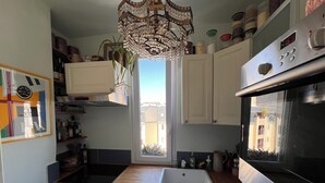 Una cocina con horno Bosch, lavavajillas, fregadero y ventana con vistas a edificios.
