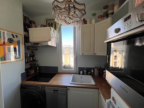 A kitchen with a Bosch oven, a dishwasher, a sink, and a window with a view of buildings. - Bright 1-bedroom Montmartre apartment w/ balcony & views of rooftops (Paris)