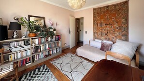 Una sala de estar acogedora con una estantería, un sofá, una mesa de centro y una alfombra estampada.