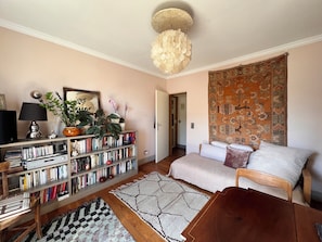 A cozy living room with a bookshelf, a sofa, a coffee table, and a patterned rug. - Bright 1-bedroom Montmartre apartment w/ balcony & views of rooftops (Paris)