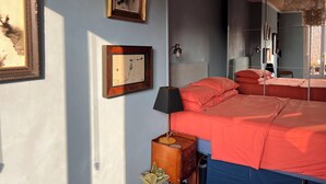 Un dormitorio con una cama, dos cuadros enmarcados, una mesita de noche, una lámpara y una lámpara colgante.