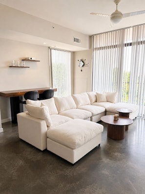 A modern living room with a sectional sofa, a round coffee table, and a dining area with a small table and chairs.