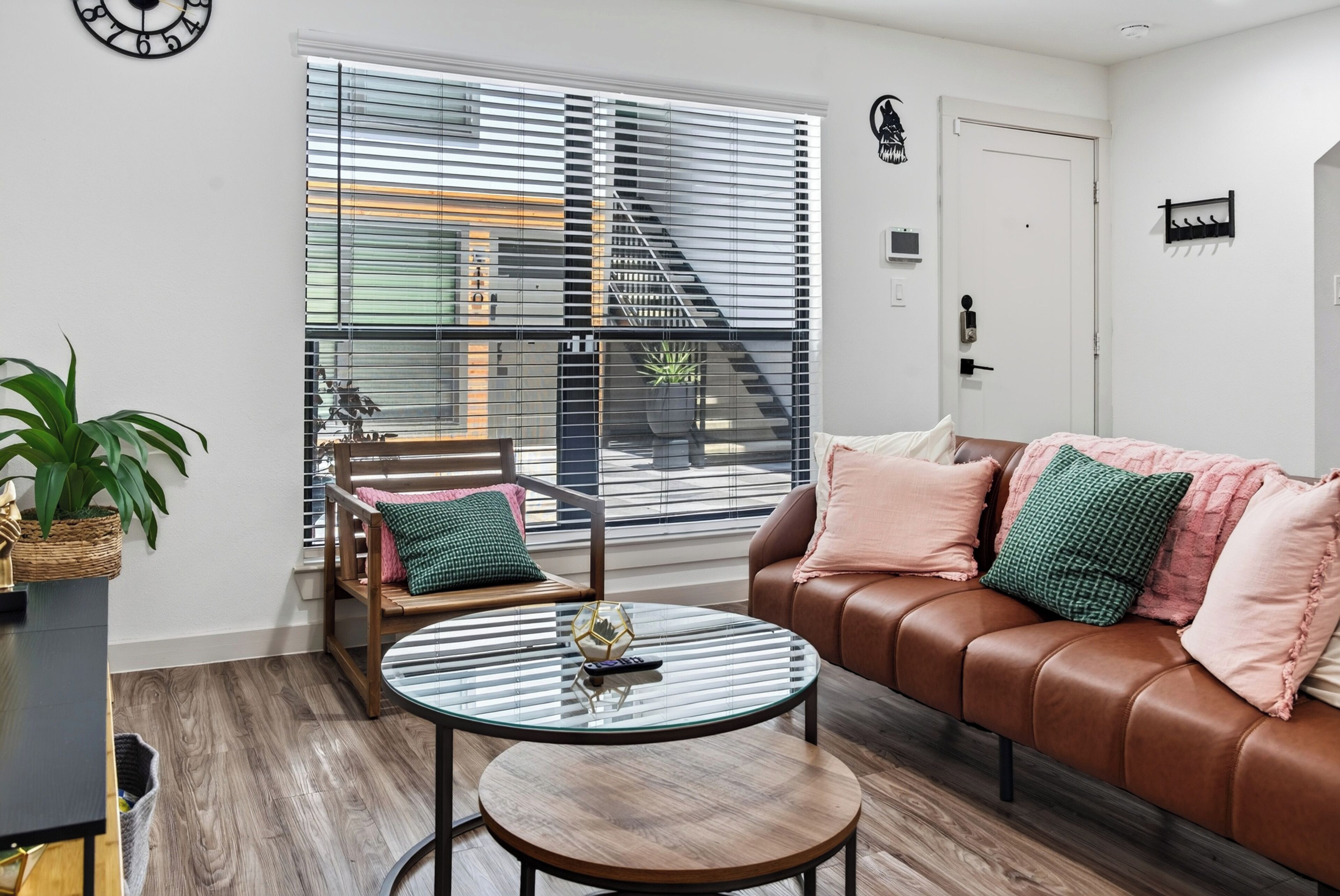 Ein modernes Wohnzimmer mit einer Ledersofa, einem Glastisch und Blick auf ein Gebäude mit einer Treppe.