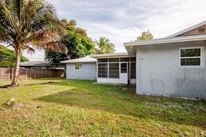 A residential property with a grassy yard, a wooden fence, and a palm tree.